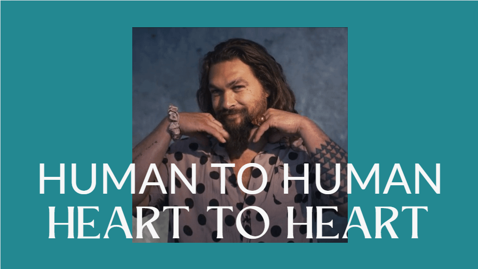 A picture of the actor Jason Mamoa with his hands framing his face and smiling. With the words Human to Human and Heart to Heart